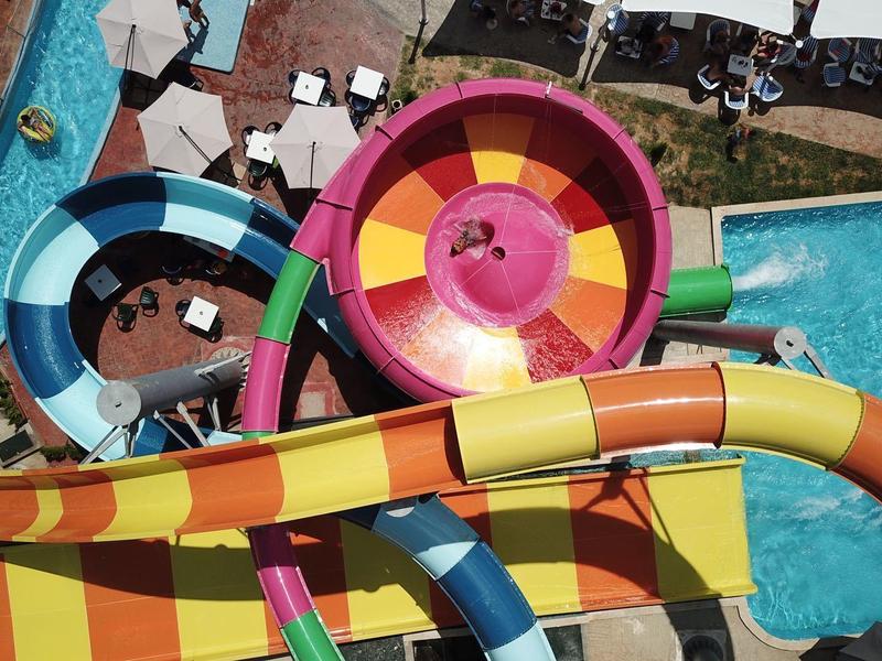 Bunte Wasserrutschen führen in einen großen Wassertrichter in einem Wasserpark.