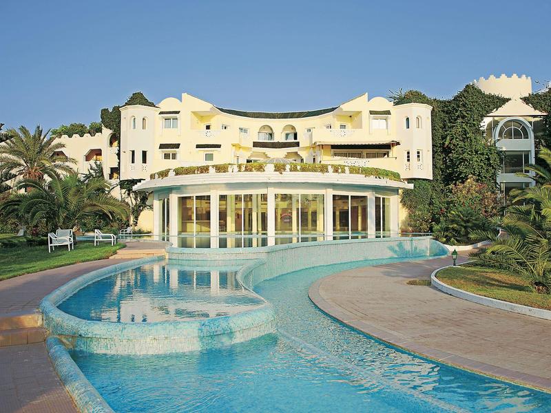 Luxushotel mit geschwungener Schwimmbadlandschaft und tropischer Vegetation.