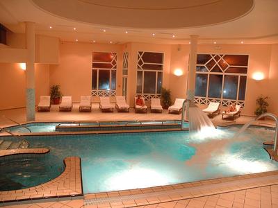Innenhallen-Pool mit Springbrunnen, Liegestühlen und warmem, sanftem Licht.