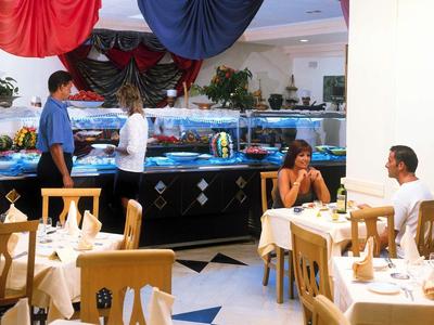 Restaurant mit Fischbecken, zwei Gästen am Tisch und zwei Mitarbeitern hinter der Theke.