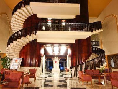 Luxuriöser Hotel-Eingang mit schwarz-weißem Marmorboden und geschwungenen Treppen links und rechts.