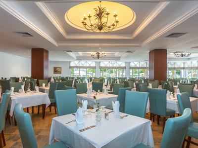 Elegant restaurant with white tablecloths and blue chairs under chandeliers