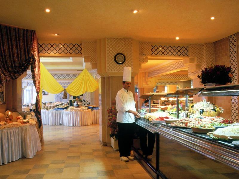 Buffet area in a hotel restaurant with a variety of food and a chef.