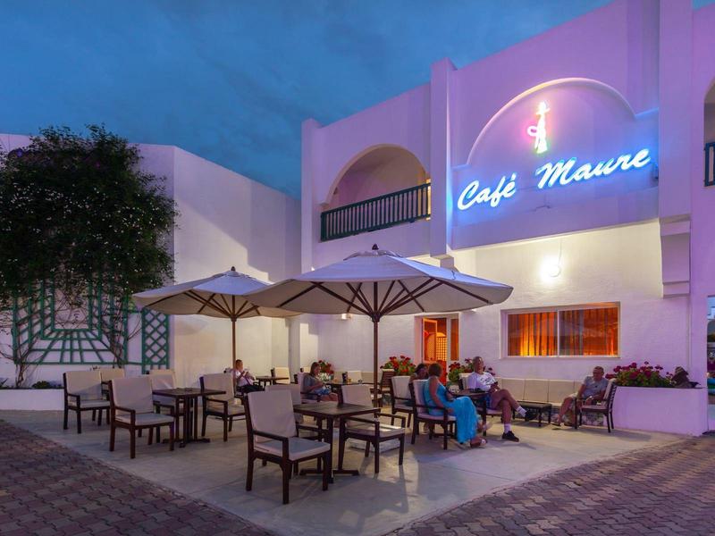 Cafe terrace with tables, chairs, and umbrellas at dusk.