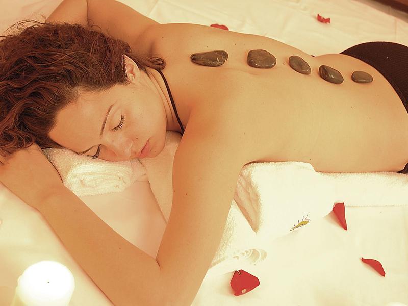 Woman relaxing during a hot stone massage with warm stones placed on her back.