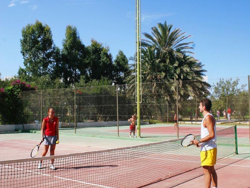Two men playing tennis on an outdoor court in sunny weather.