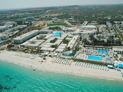 Veduta aerea di un grande resort con più piscine accanto a una spiaggia turchese.