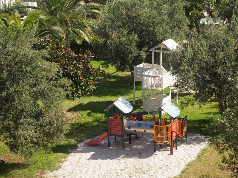 Parco giochi per bambini con struttura per arrampicata e scivolo in un'area verde.