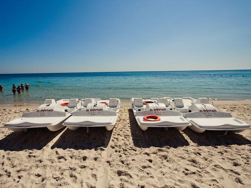 Sdraio vuote in due file sulla spiaggia con vista sul mare sotto un cielo limpido.