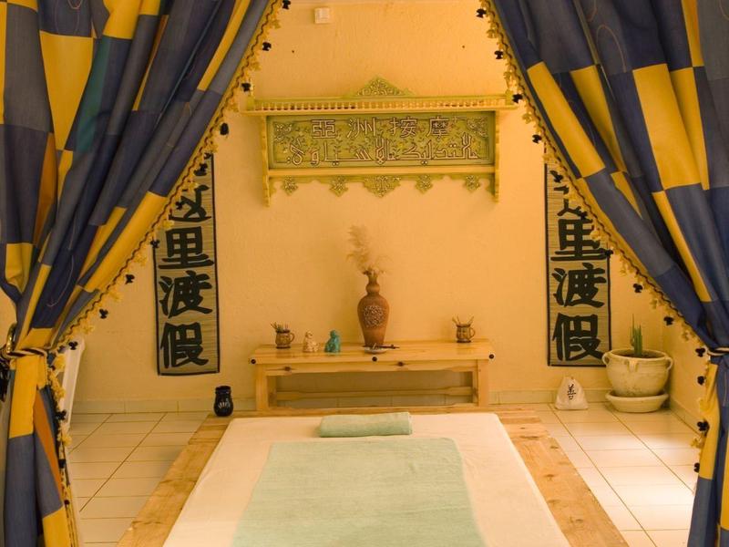 Elegante sala de spa con una bañera empotrada, enmarcada por cortinas amarillas y azules.