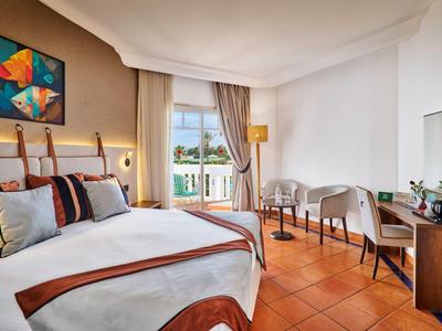 Habitación de hotel moderna con cama grande, escritorio y vista a la terraza.