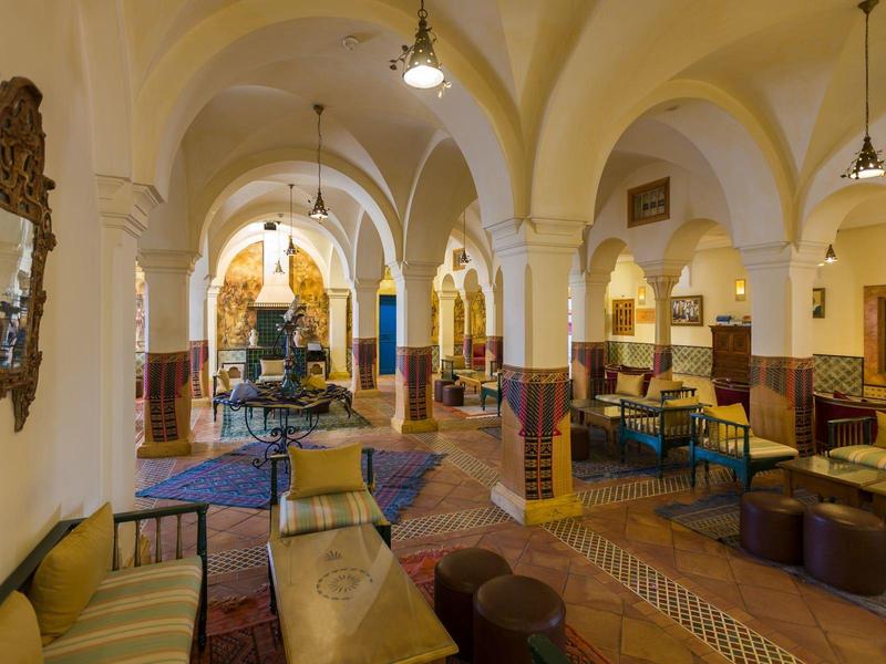 Spacious hotel lounge with arches, seating areas, and warm lighting.