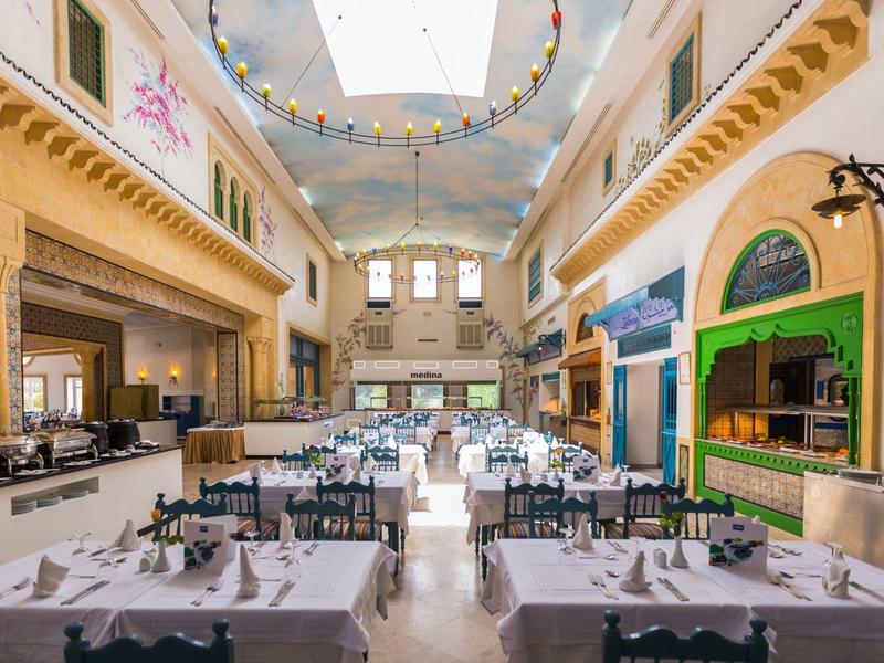 Elegant hotel restaurant with white tablecloths and bright natural light.