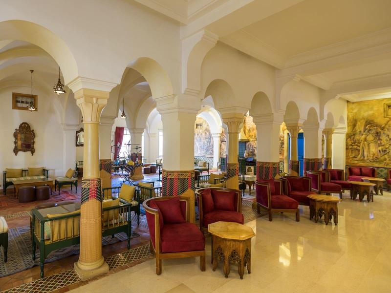Bright, elegant hotel interior with columns, red armchairs, and comfortable sofas in an open space.