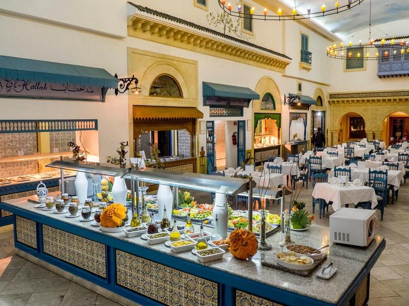 Elegant buffet setup in a spacious hotel dining area with tables and white chairs.