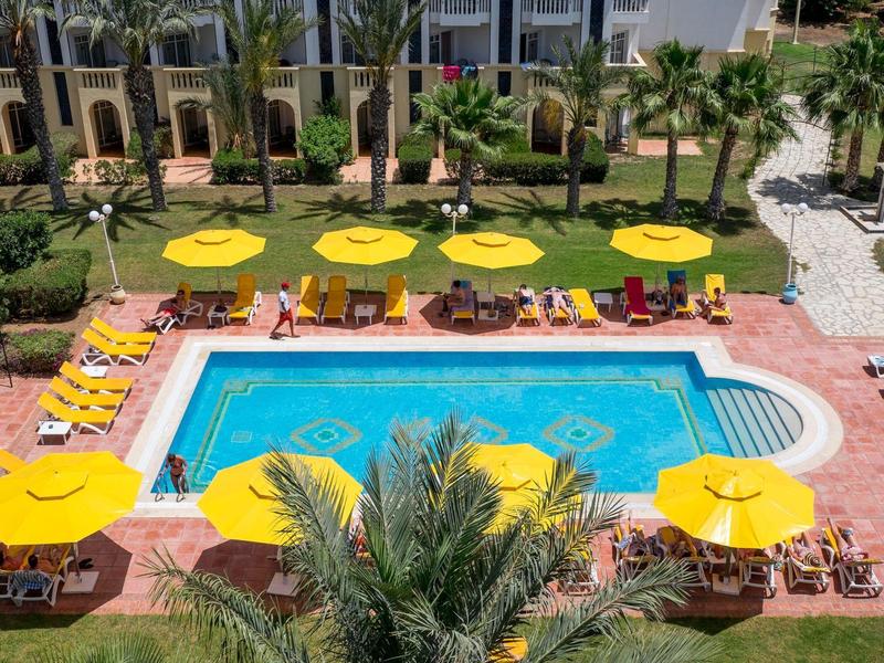 Top view of a hotel pool area with yellow umbrellas and sun loungers.