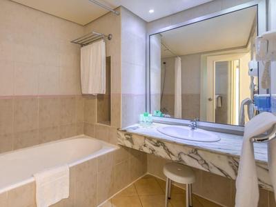 Helle Hotelbadezimmer mit Badewanne, großem Spiegel und Marmorwaschtisch.