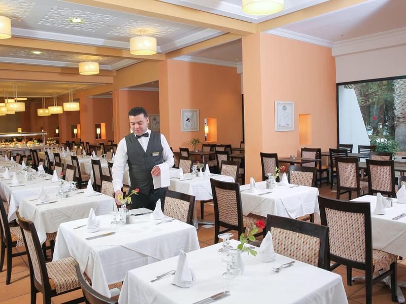 Ein elegantes Restaurant mit gedeckten Tischen und einem Kellner im Anzug.