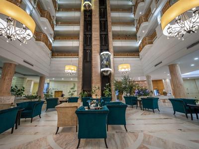 Moderner Hotel-Lobby mit erhöhten Sitzbereichen und Aufzügen in der Mitte.