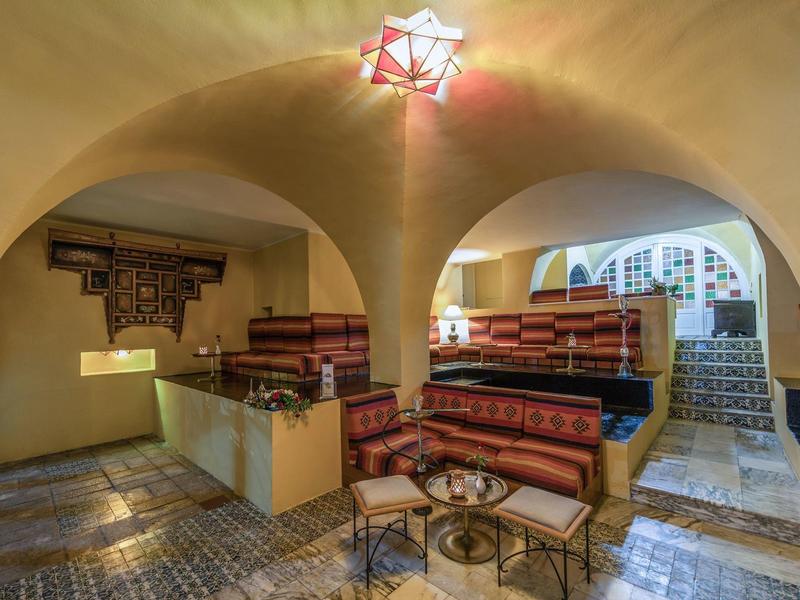 Gemütlicher Lounge-Bereich mit gepolsterten Sitzbänken, Rundbögen und warmem Licht im Hotel.