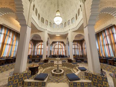 Wnętrze z efektowną kopułą, kolumnami, centralną fontanną i miejscami do siedzenia z kolorowymi kafelkami.