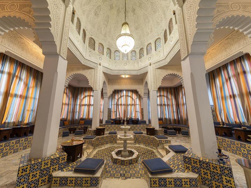 Wnętrze z efektowną kopułą, kolumnami, centralną fontanną i miejscami do siedzenia z kolorowymi kafelkami.