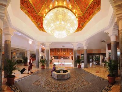 Luxuriöse Hotellobby mit großem Kronleuchter, Mosaikboden und eleganten Säulen.