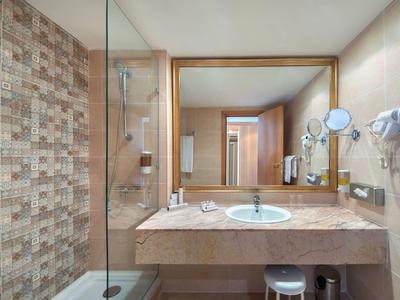 Modernes Badezimmer mit Fliesenwand, Glasdusche, Waschbecken auf Marmorwaschtisch und großen Spiegel.
