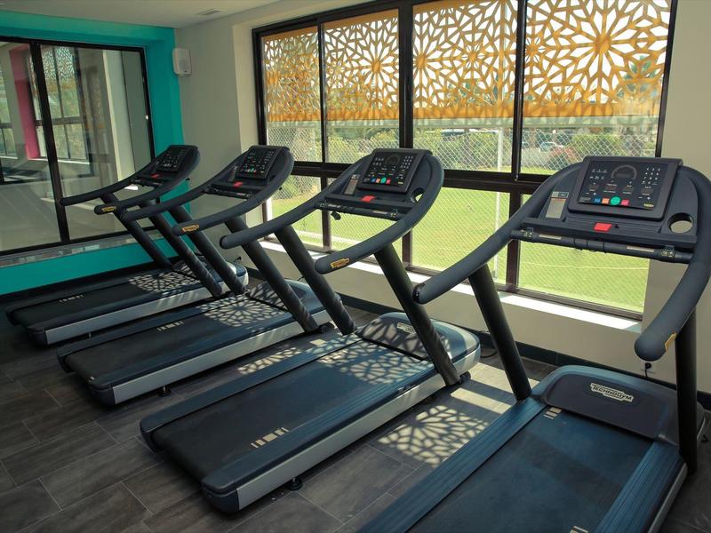 Tapis roulant moderni in una palestra luminosa con grandi finestre.