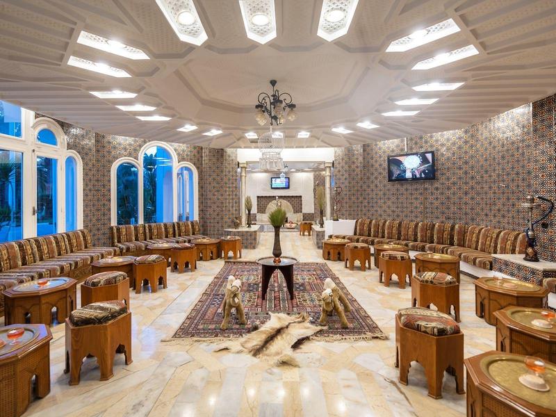 Ampio salone d'hotel con sedute in pelle e grandi finestre luminose.