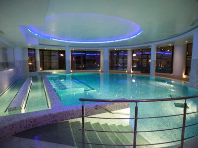 Nowoczesny, oświetlony kryty basen hotelowy z oknami ze szkła i schodami.