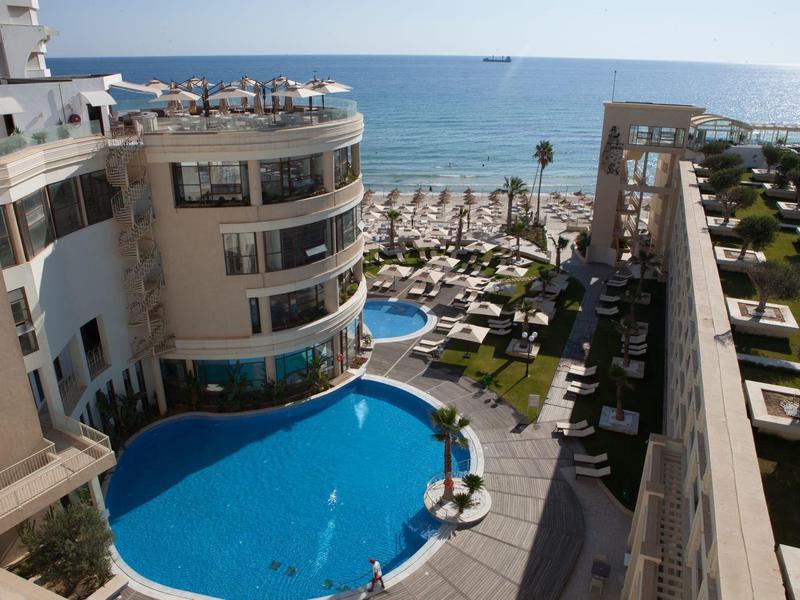 Hotel z dużym basenem, parasolami i widokiem na morze