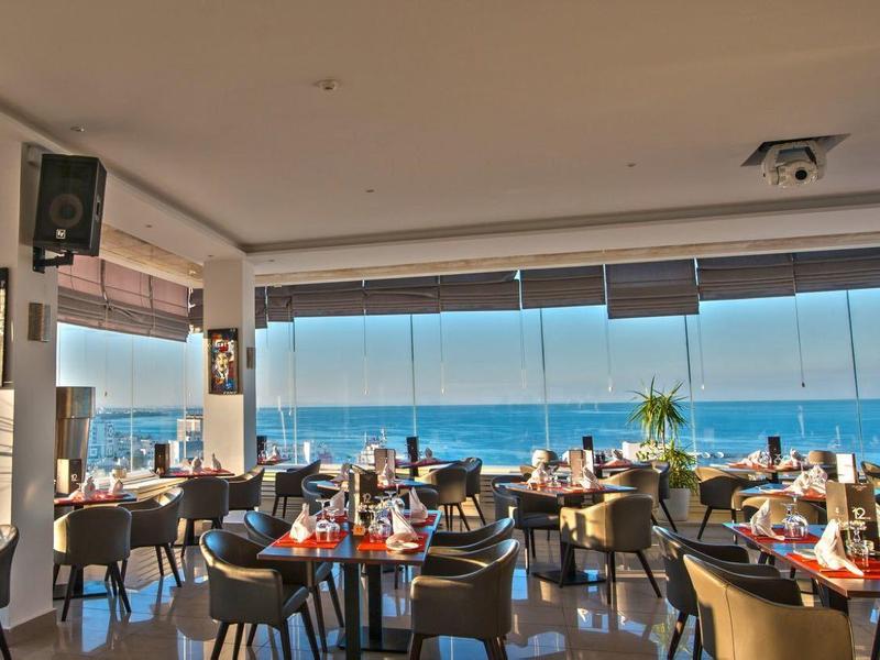 Jasna restauracja z widokiem na morze i elegancko nakrytymi stołami.