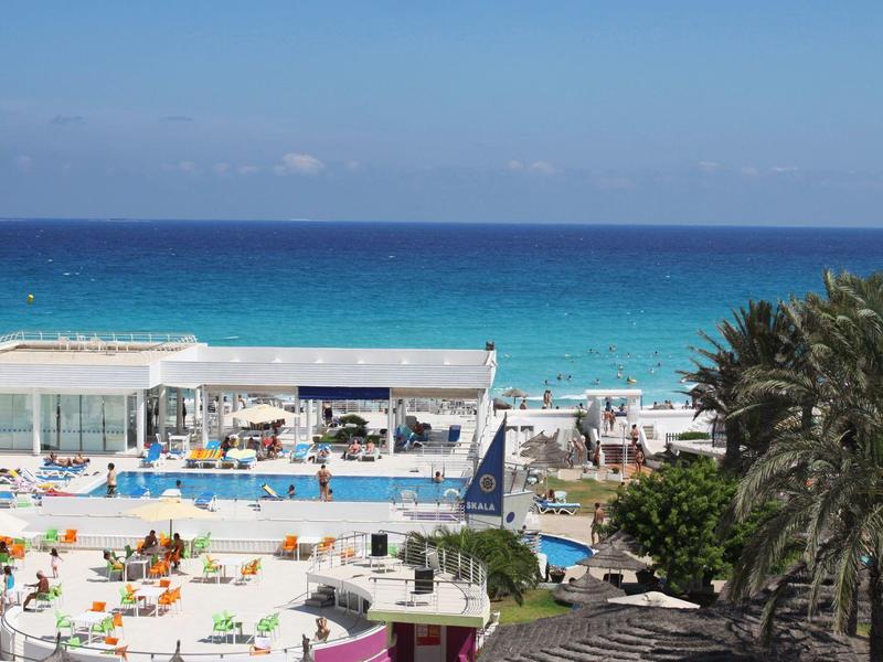 Vue sur une zone de piscine avec la mer en arrière-plan par une journée ensoleillée.
