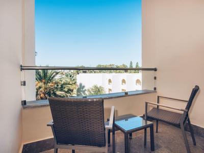 Balcone con tavolo e sedie con vista su palme e cielo limpido.