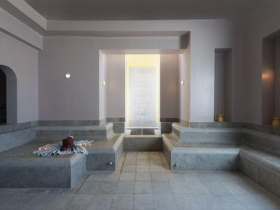 Area spa moderna e tranquilla con lettini in pietra e illuminazione soffusa.