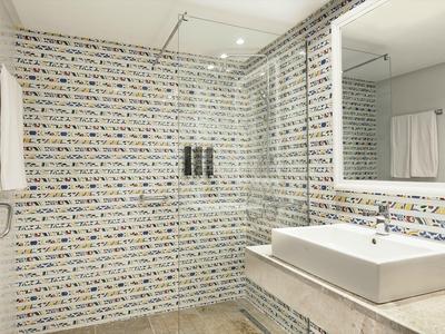 Modernes Badezimmer mit quadratischem Waschbecken und Glasdusche, weiße und graue Fliesen.