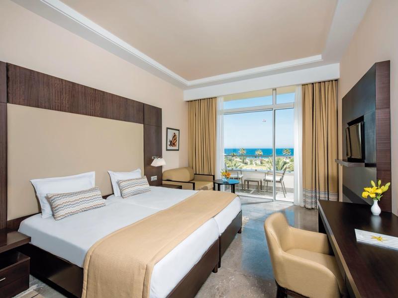 Camera d'hotel luminosa con vista mare e balcone.