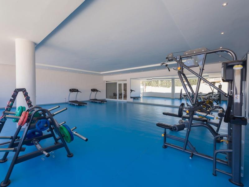 Palestra con pavimento blu, attrezzature per l'allenamento e grandi finestre con luce naturale.