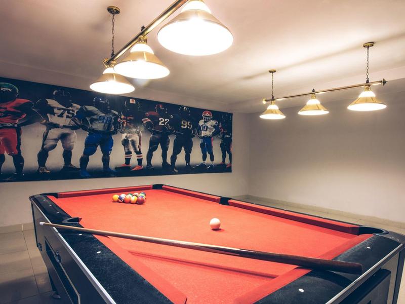 Un tavolo da biliardo rosso in una stanza accogliente con illuminazione moderna e arte murale.