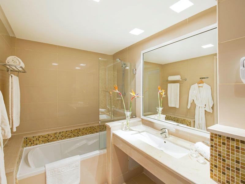 Bagno luminoso con vasca, grande specchio e due lavandini.