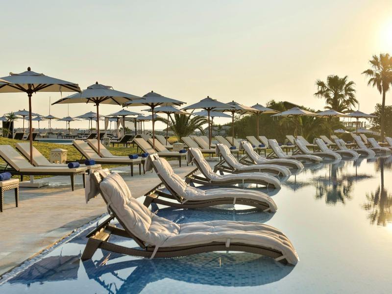 Piscina con lettini e ombrelloni al tramonto in un resort.