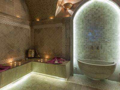 Spa moderne avec carrelage mosaïque, bancs chauffants et bassin d'eau éclairé.