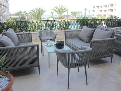 Terrasse mit modernen Möbeln und Blick auf Palmen und Gebäude.
