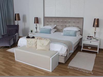 Elegantes Hotelzimmer mit Doppelbett, Stuhl, Nachttischen und warmem Holzboden.