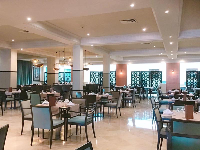 Helles, modernes Restaurant mit vielen Tischen und Stühlen, dekorativen Trennwänden und Deckenbeleuchtung.