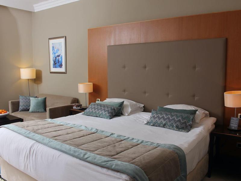 Modern eingerichtetes Hotelzimmer mit großem Doppelbett und weichen Kissen.