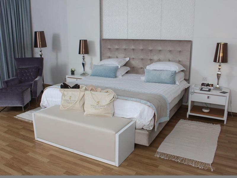 Elegantes Hotelzimmer mit Doppelbett, Stuhl, Nachttischen und warmem Holzboden.