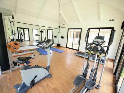 Heller Fitnessraum mit modernen Geräten und Holzboden in einem Hotel.