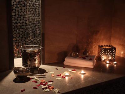 Pohodová spa atmosféra s svíčkami, okvětními lístky růží a koupelnovými doplňky na povrchu.